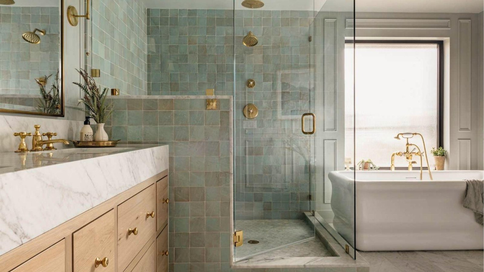 Bright bath with seafoam zellige tile, marble vanity, wood cabinets, and gold tub fixtures.