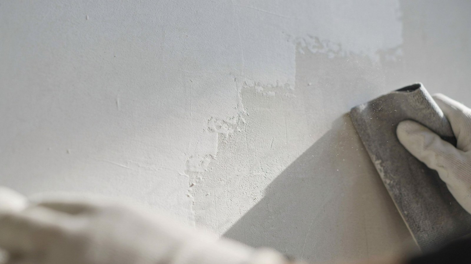 Painted wall being sanded to remove gloss and create rough texture improving surface for better primer and paint adhesion.