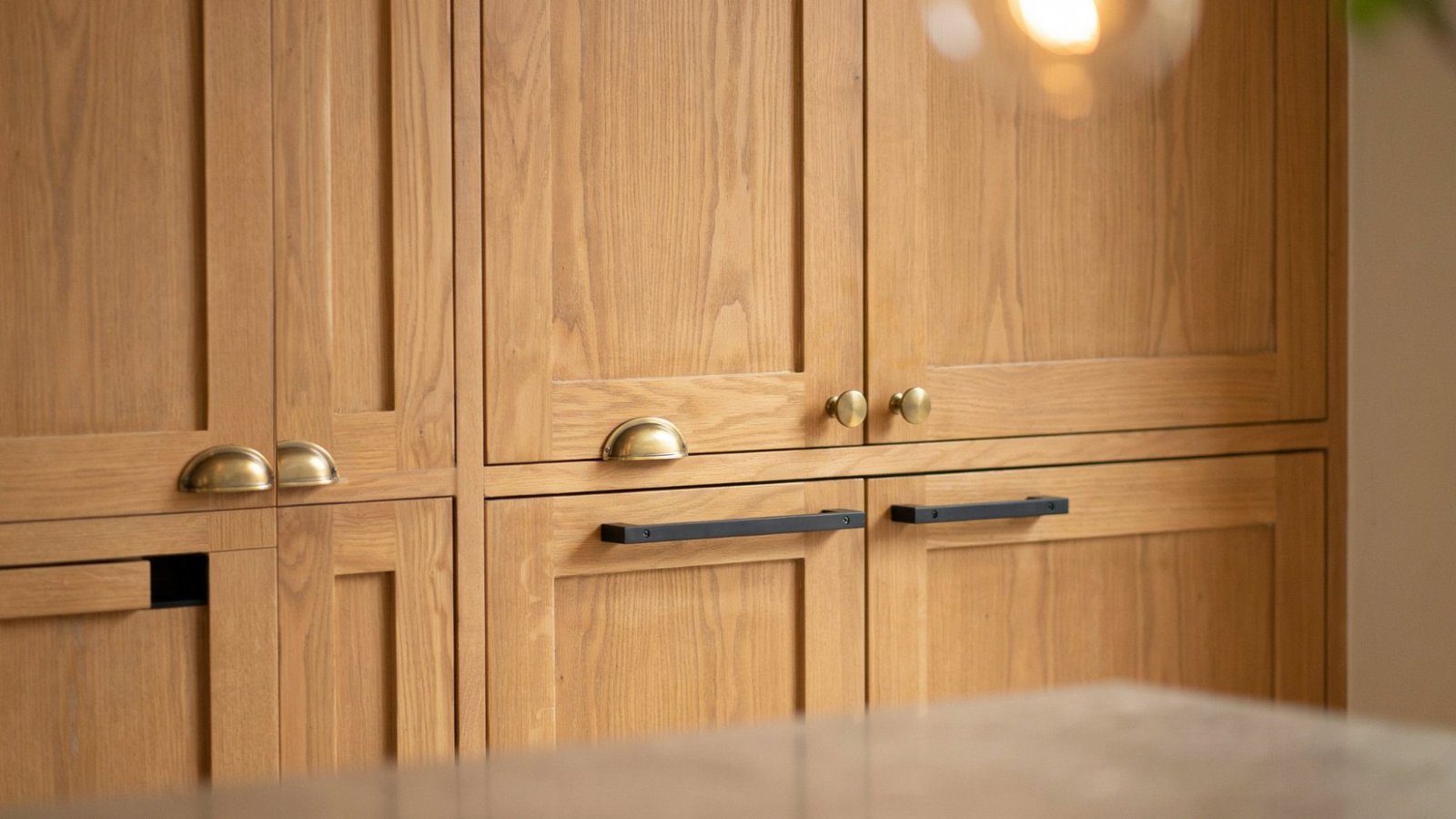 Oak kitchen cabinets featuring modern brass and black hardware upgrades.