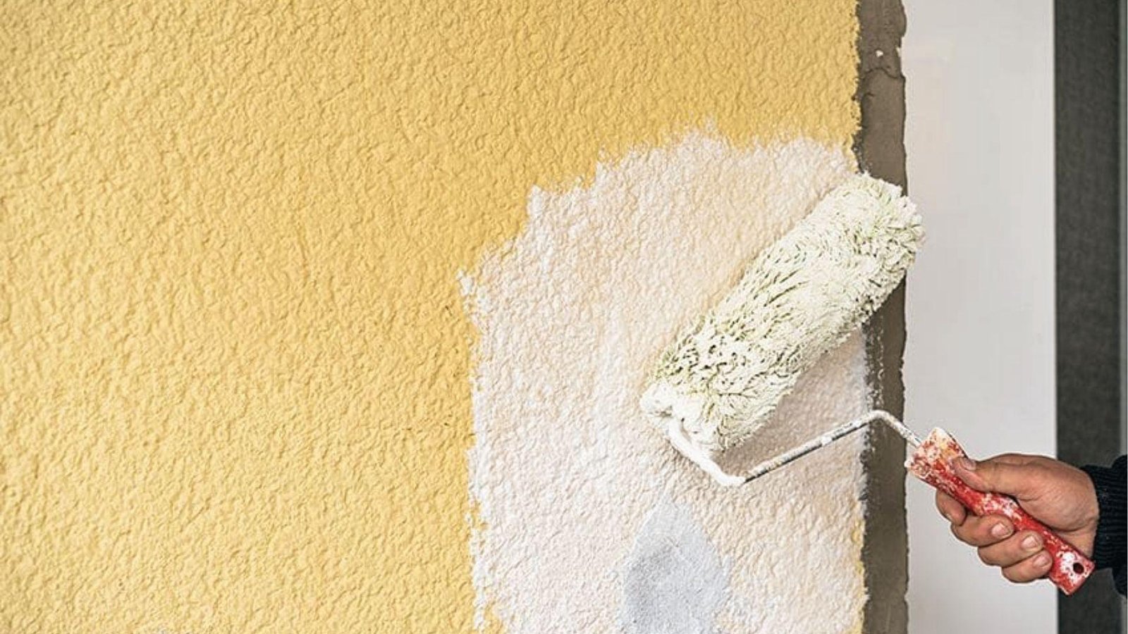 Hand applies a thick elastomeric coat over a yellow stucco wall hiding cracks for waterproofing.