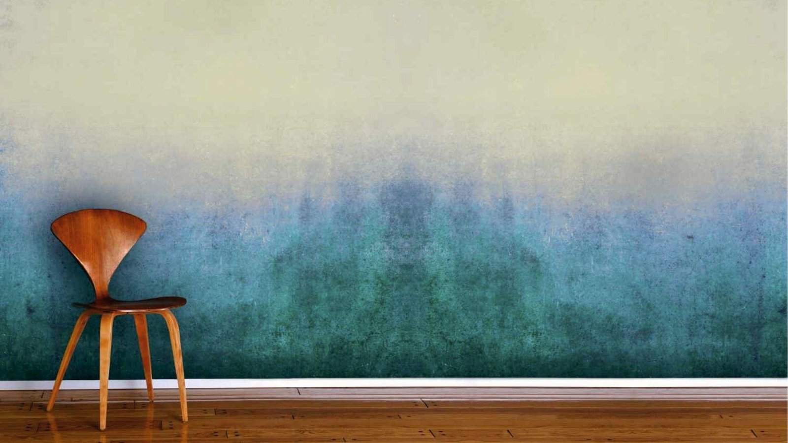 Ombre faux finish wall blends teal to cream with wooden chair, showcasing color wash technique