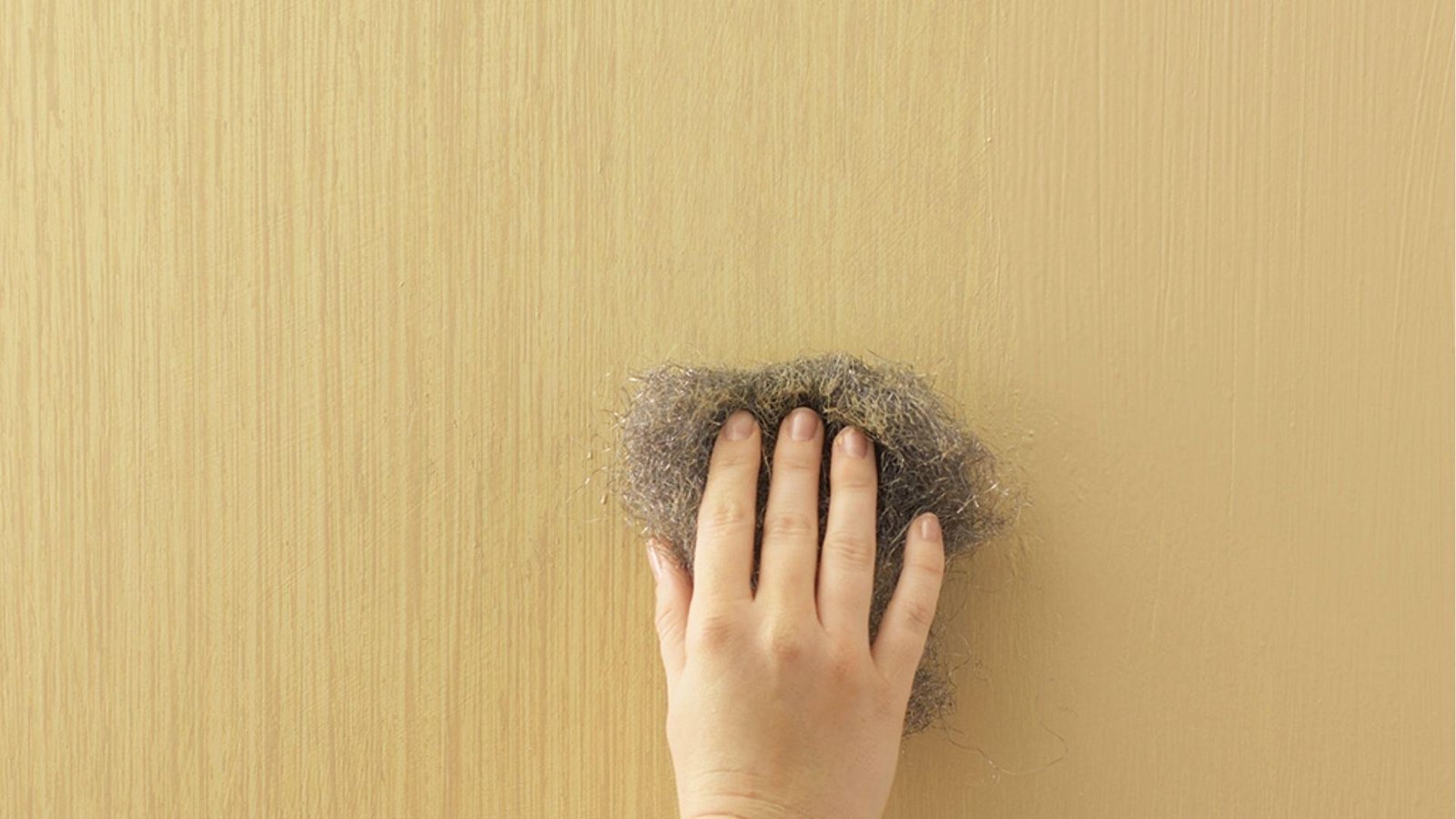 Steel wool creates vertical faux wood grain texture on beige wall, strie painting technique shown