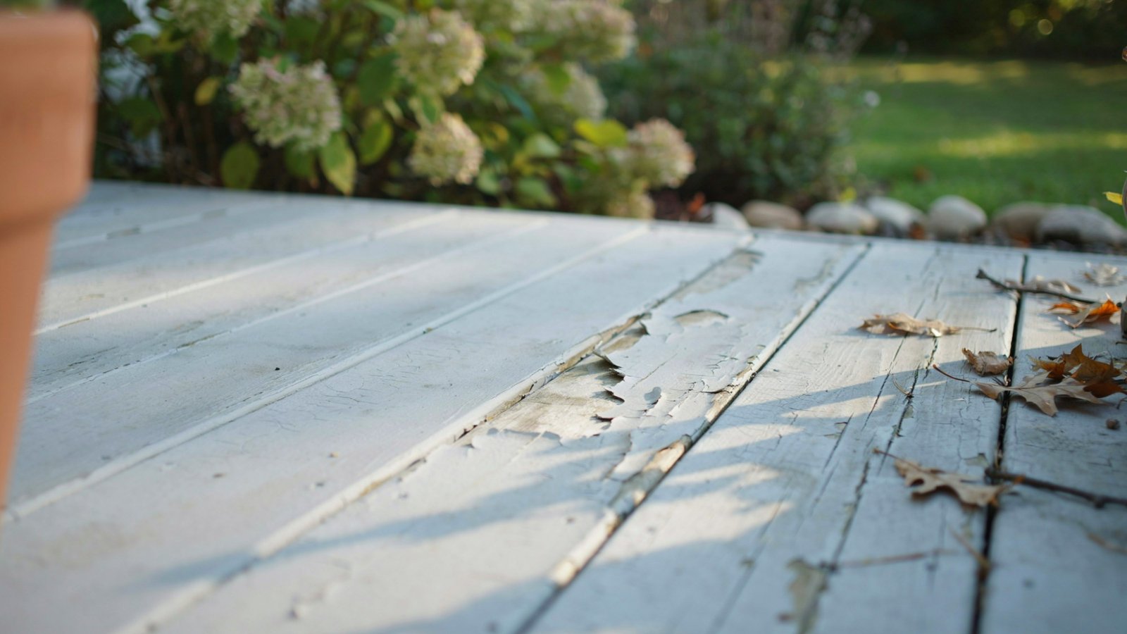 Interior paint applied on outdoor wooden surface showing fading peeling and damage under sunlight exposure in natural outdoor environment.