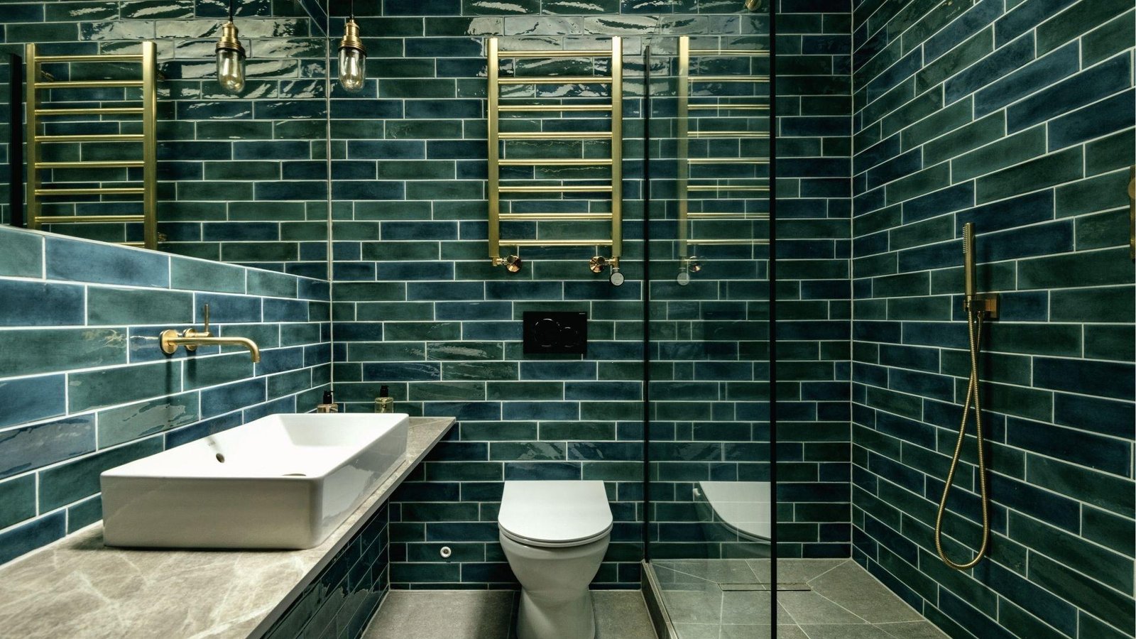 Modern bathroom with teal subway tile walls, gold towel warmers, vessel sink, and glass shower.