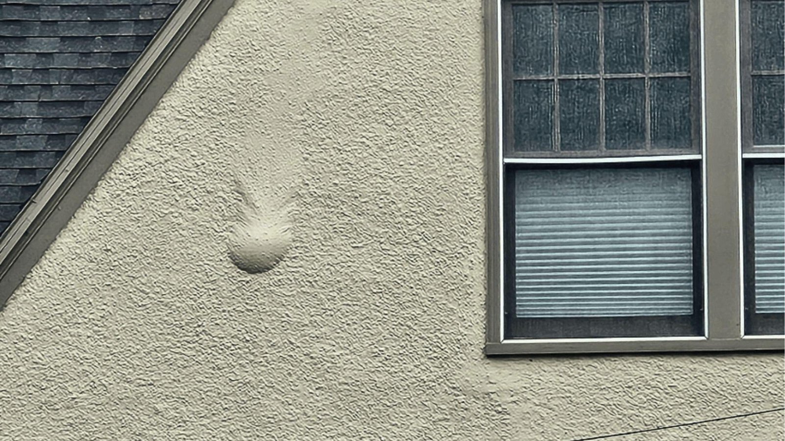 A large bubble on the exterior wall shows elastomeric paint disadvantage, trapped moisture causes failure.