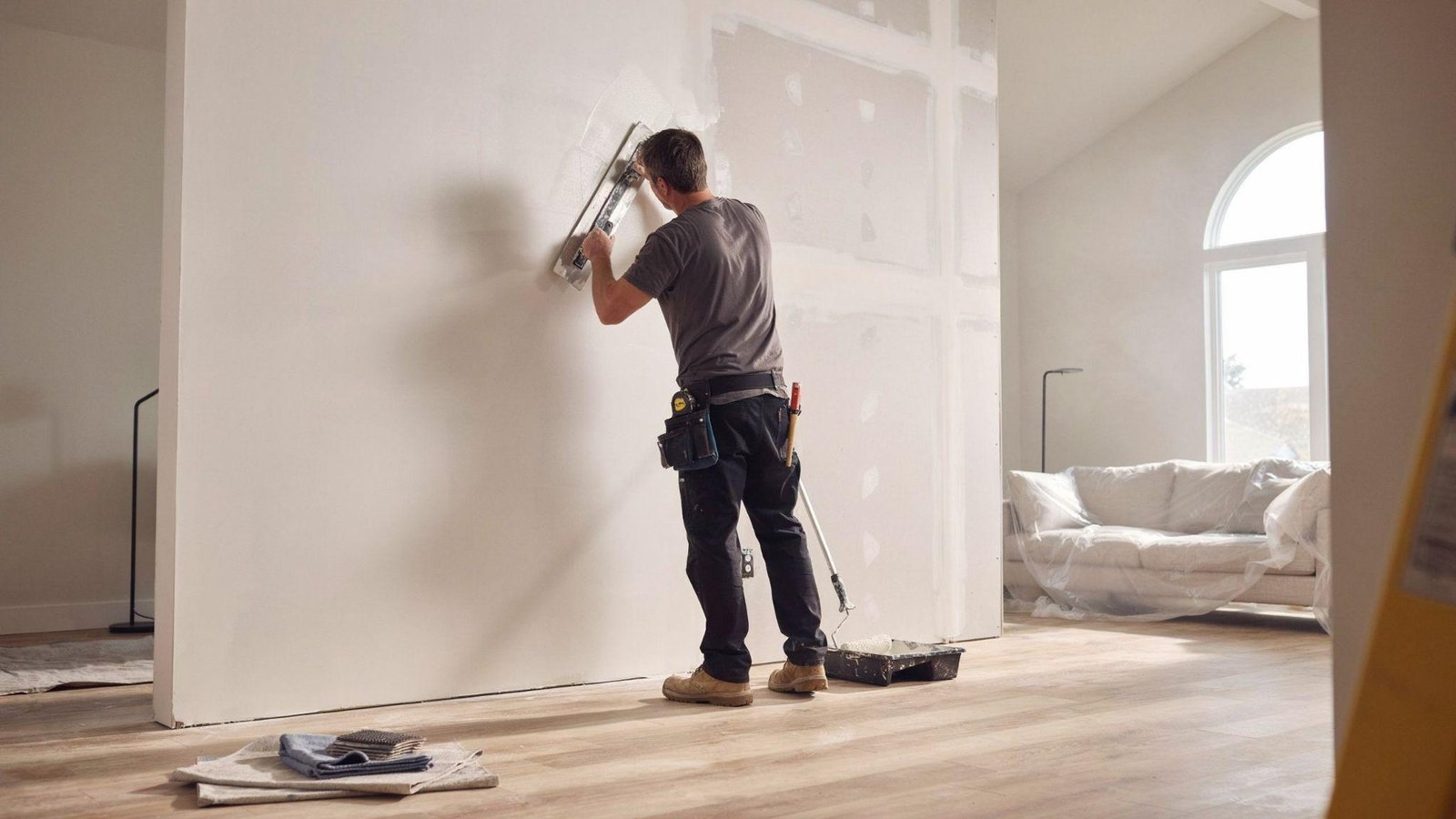 Smooth wall skim coating process in modern home renovation with contractor finishing drywall surface