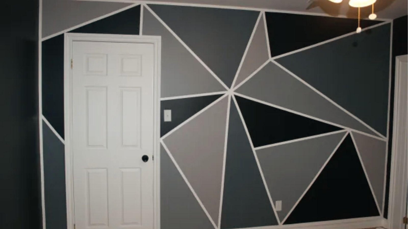 Monochrome gray geometric triangle tape accent wall with white lines around bedroom white door