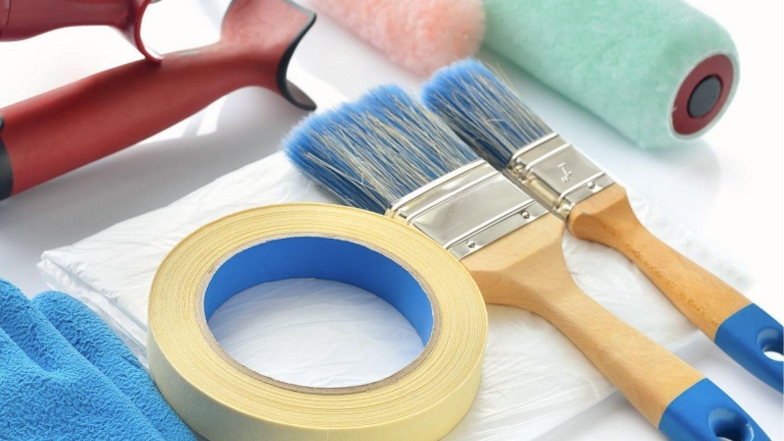 Painting tools flat lay with painter's tape roll, brushes, and rollers for DIY accent wall prep