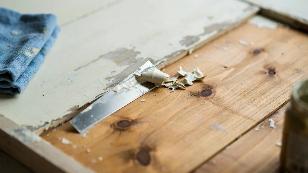 Scraping away softened paint after applying paint stripper